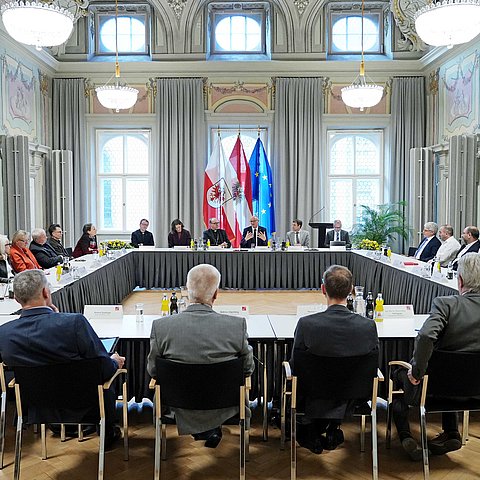 Mehrere Personen sitzen an in einem Viereck angeordneten Tischen im Parissaal.