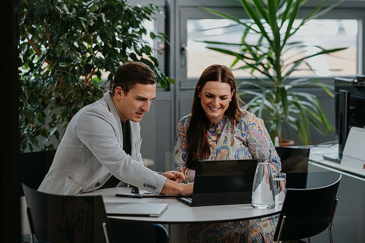 Mann und Frau sitzen am Tisch und arbeiten an Laptop