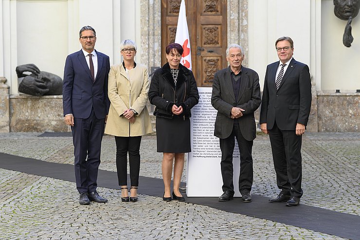 (v.li.) LH Arno Kompatscher, LRin Giulia Zanotelli, LTPin Sonja Ledl-Rossmann, Felix Mitterer und LH Günther Platter auf der symbolischen Grenzlinie, die durch die Fahne der Euregio durchbrochen wird.