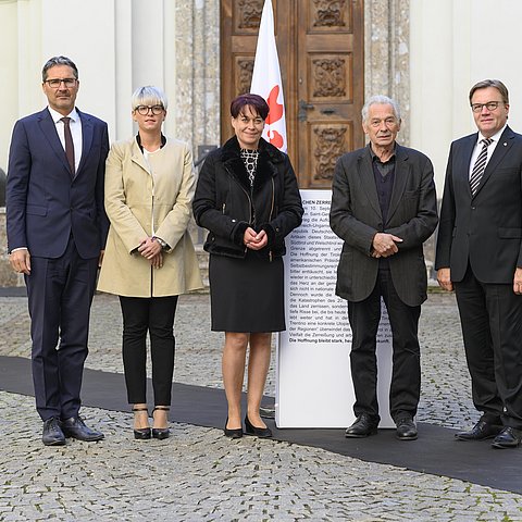 (v.li.) LH Arno Kompatscher, LRin Giulia Zanotelli, LTPin Sonja Ledl-Rossmann, Felix Mitterer und LH Günther Platter auf der symbolischen Grenzlinie, die durch die Fahne der Euregio durchbrochen wird.