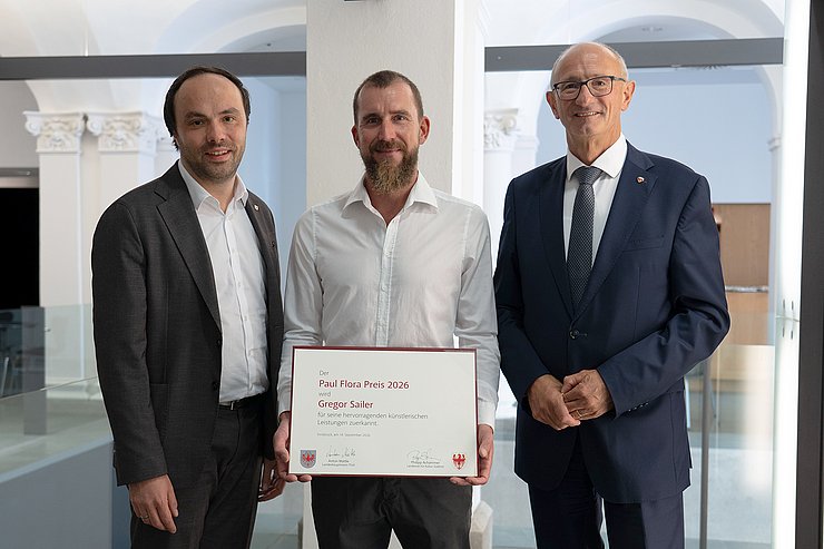 © Land Tirol/Sidon Landeshauptmann Anton Mattle (re.) und Südtirols Kulturlandesrat Philipp Achammer (li.) haben den Paul-Flora-Preis 2026 an Gregor Sailer überreicht.