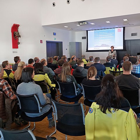 Die rund 50 Teilnehmenden sitzen im Saal und werden von der Bezirkshauptfrau begrüßt