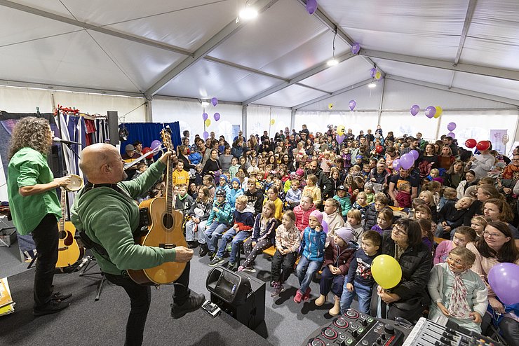 © Land Tirol/Die Fotografen Bühne mit Sänger, der Gitarre spielt. Im Hintergrund Publikum