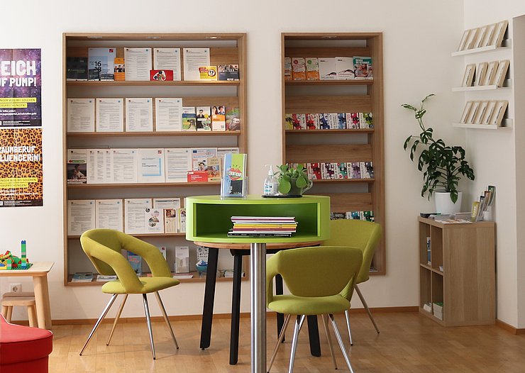 Raum mit einem Tisch und drei grünen Stühlen um den Tisch herum. 