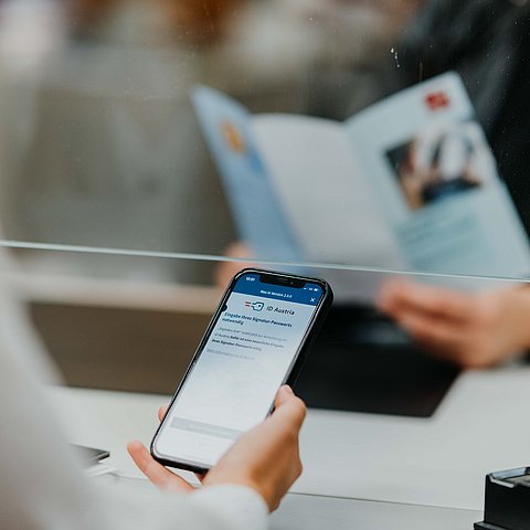 Person beim Bürgerservice hält Handy in der Hand