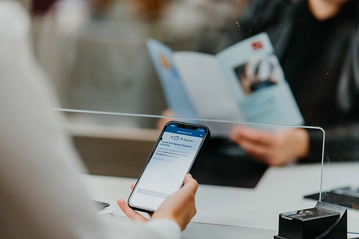Person beim Bürgerservice hält Handy in der Hand