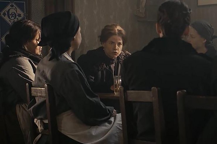 Fünf Frauen sitzen gemeinsam an einem Tisch und besprechen ernste Themen.