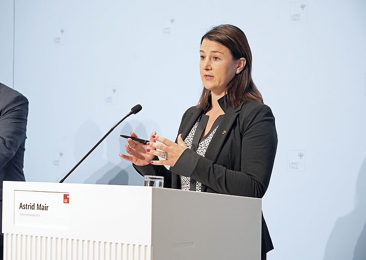 Eine Frau steht an einem Rednerpult und gestikuliert mit beiden Händen.