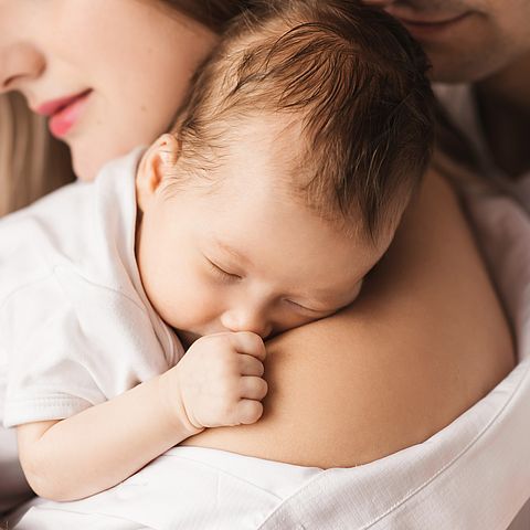 Symbolbild junger Eltern mit Baby auf dem Arm