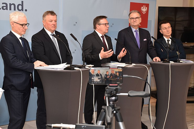 Die Teilnehmer der Pressekonferenz stehen an den Rednerpulten.