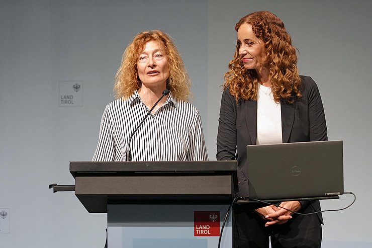 Personen stehen nebeneinander, Hüttemann spricht in Mikro