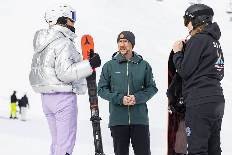 Mario Gerber spricht mit einer Skifahrerin und einer Snowboarderin